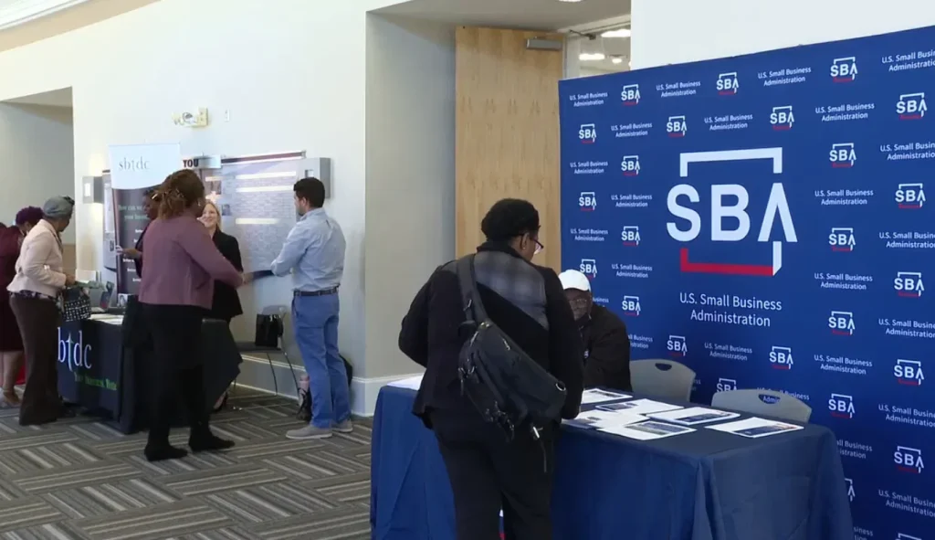 A photo of a crowded SBA conference hall with attendees listening to a speaker on stage.